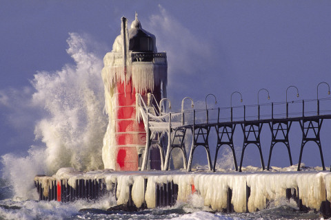 An icy wave breaks on the lighthouse at South Haven Michigan during a winter squall.
